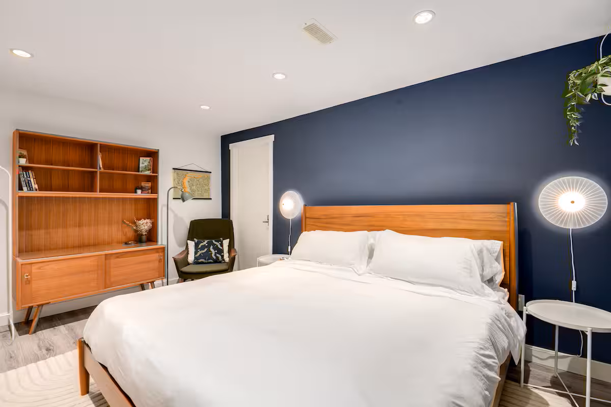 The main bedroom, with a king bed against a navy wall and a teak shelf