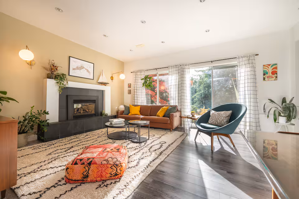 The living room, with a gas fireplace, an orange sofa and sliding doors onto the patio
